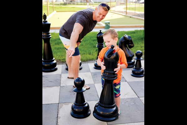 A father and son playing life-sized chess at The Lodge at Geneva